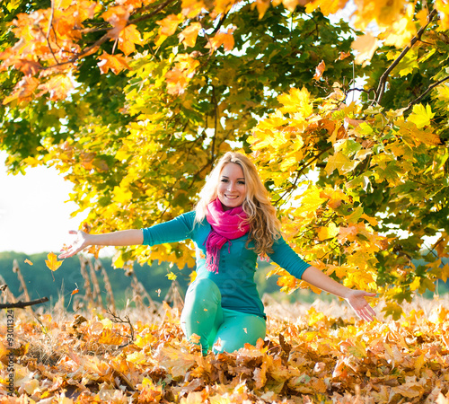 blond young girl drop up leaves in autumn color