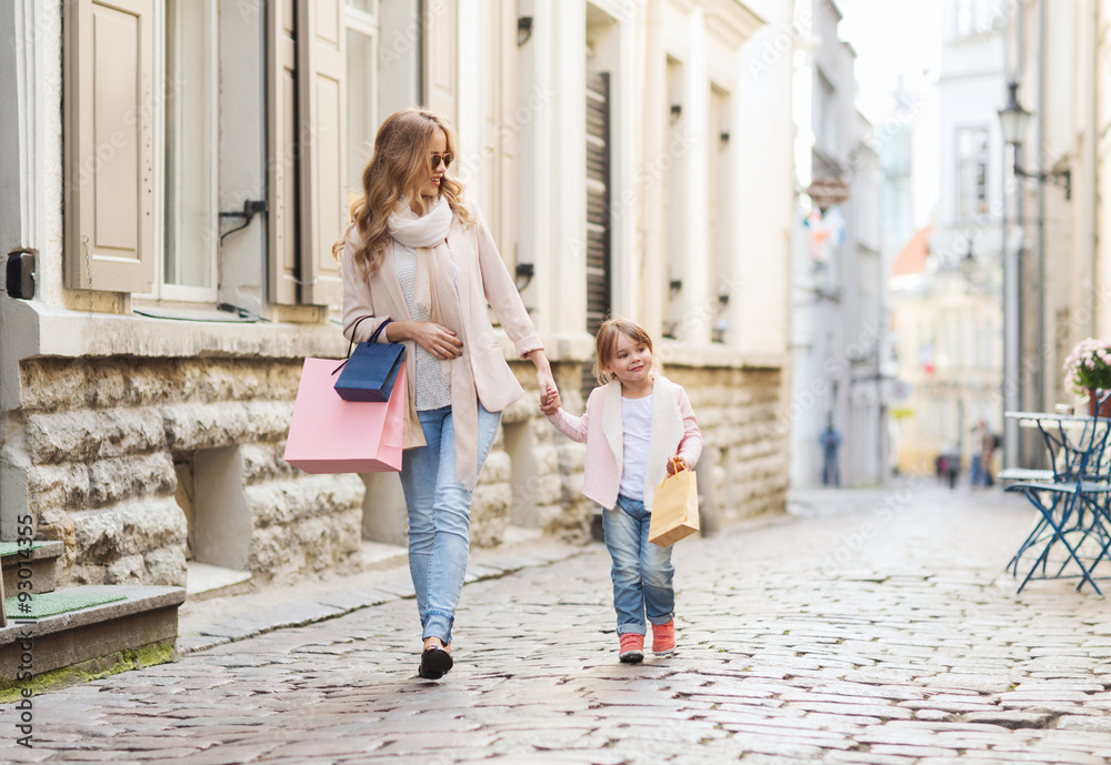 happy mother and child with shopping bags in city