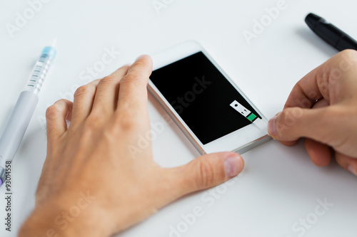 close up of man with smartphone making blood test
