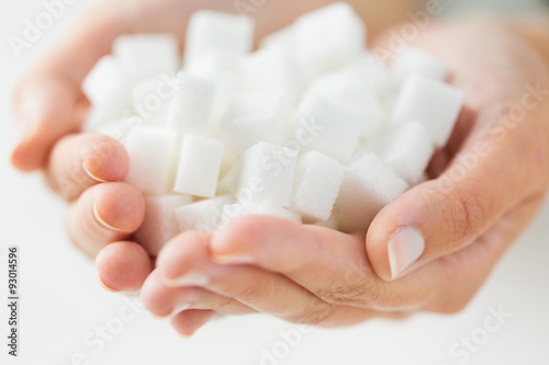 Photos close up of white lump sugar in woman hands