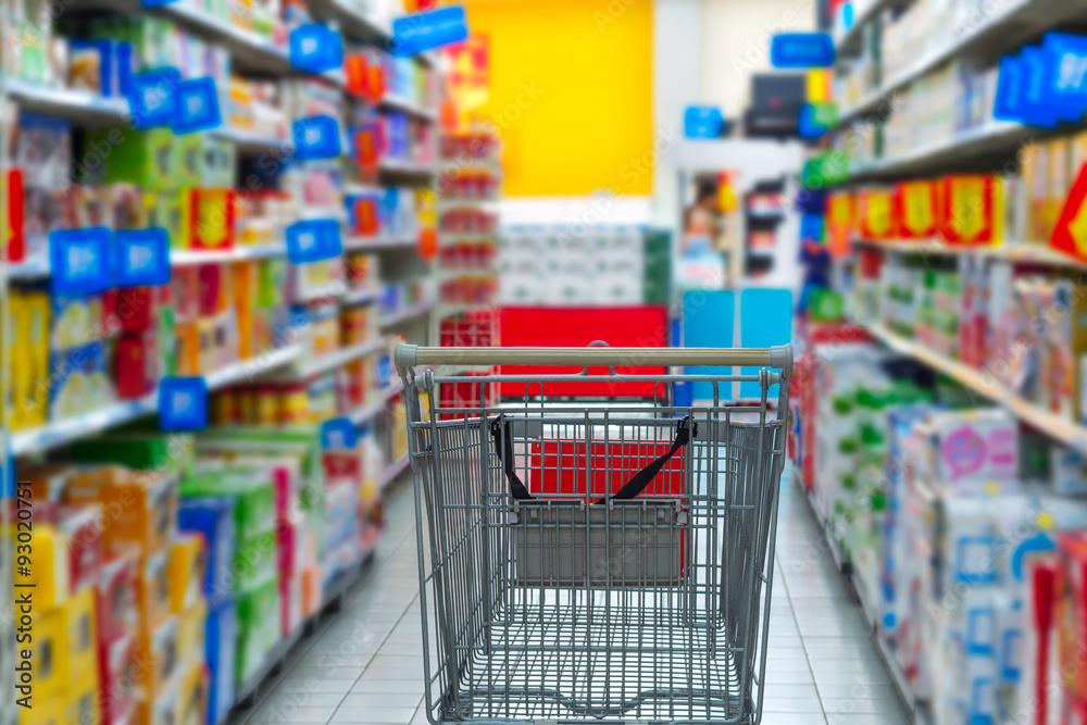 Supermarket interior, empty red shopping cart.