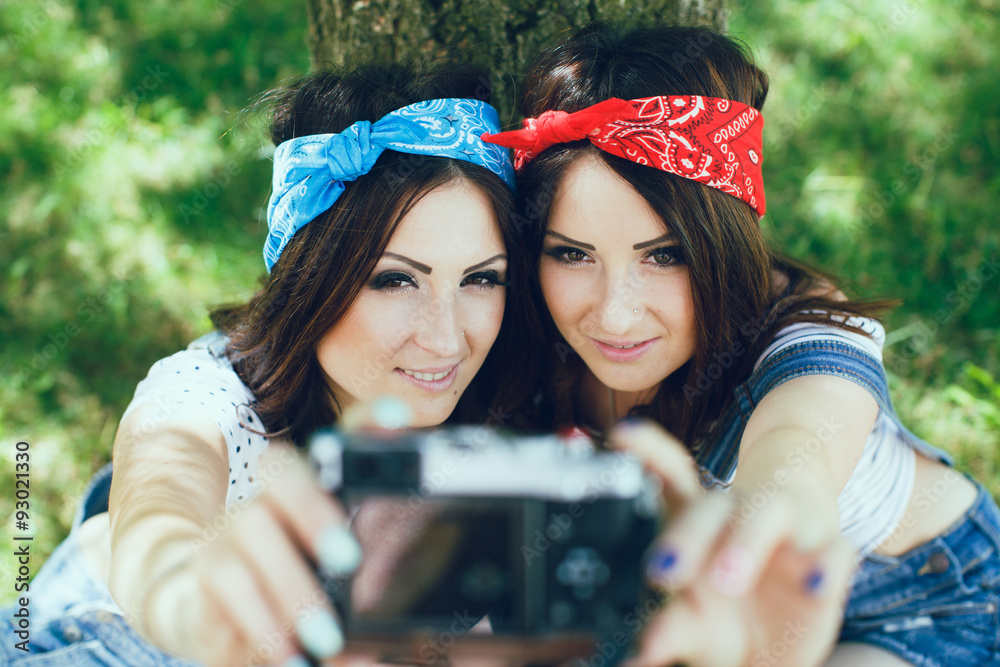 cute twins girls taking selfie with camera in the park.