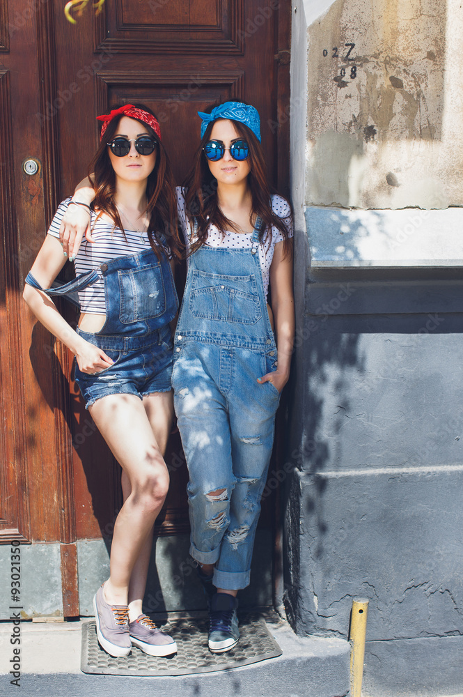 twins sisters, in stylish sunglasses, hugging.