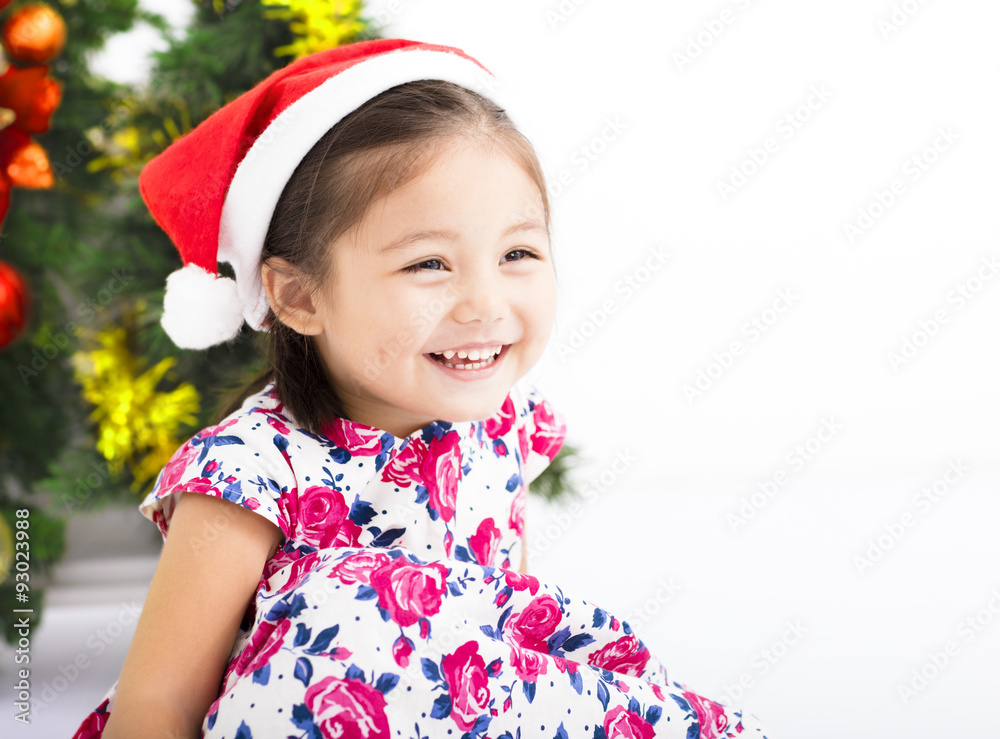 happy little girl with Santa hat in front of christmas tree happy little girl with Santa hat in front of christmas tree
