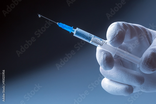 Medical syringe with needle in hand doctor. At the end of the needle drop of liquid