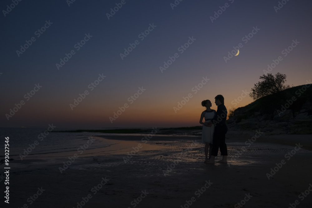 Silhouette of a girl and guy night on the coast