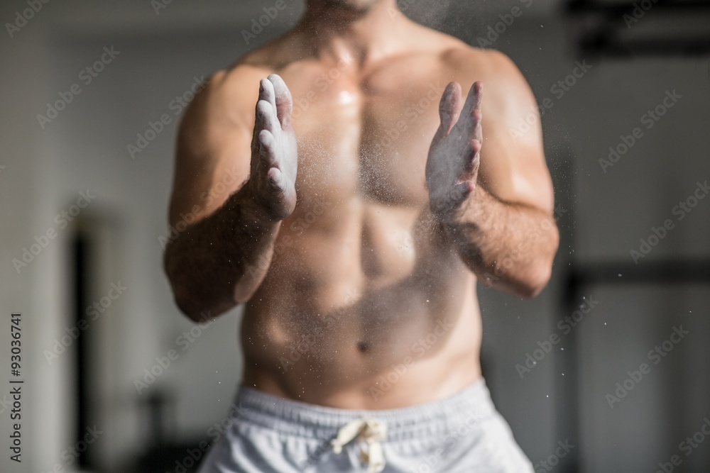 Fototapeta premium Muscular man shaking chalk off his hands