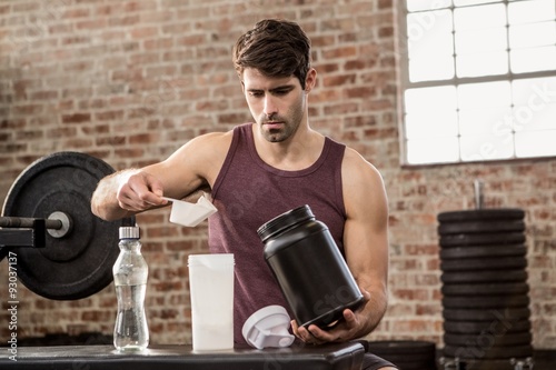 Man adding supplement from tin to bottle photo
