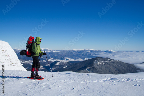 Winter hiking in the mountains on snowshoes with a backpack and tent.