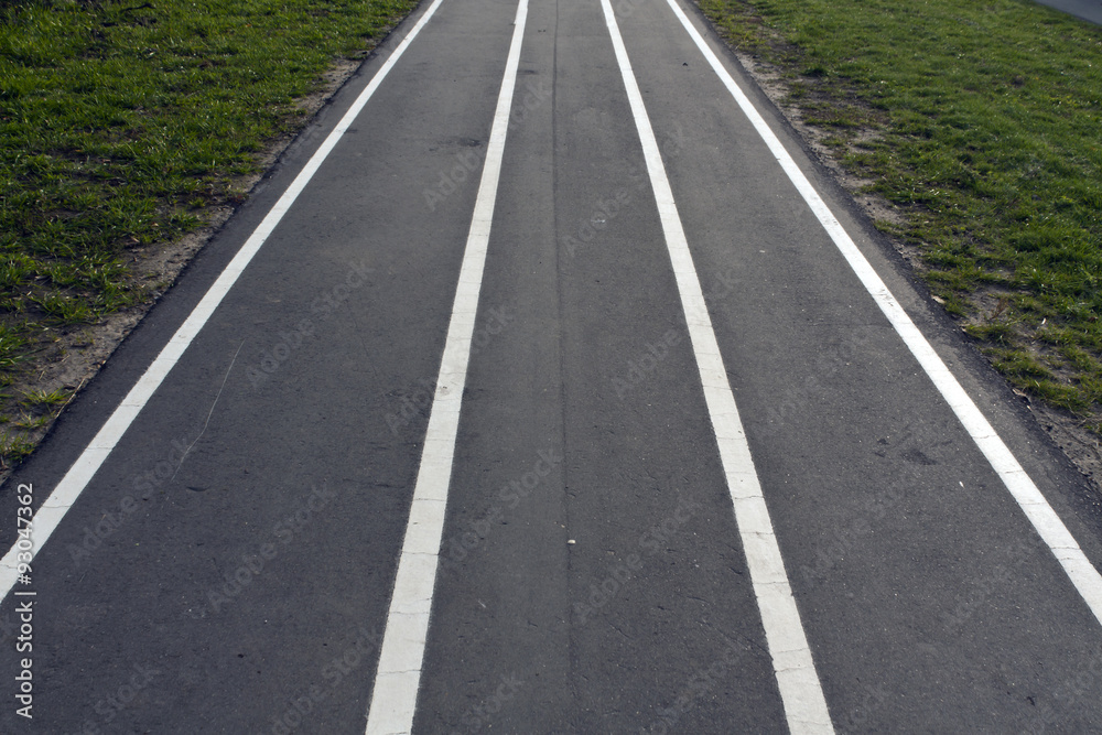 Running asphalt track with white painted lines.