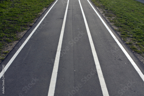Running asphalt track with white painted lines.