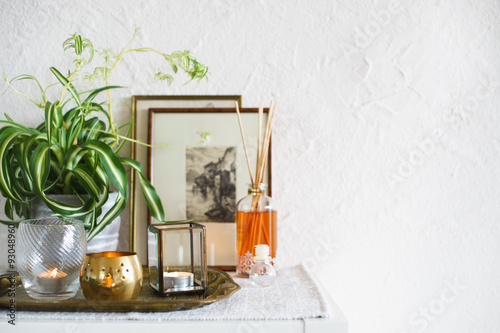 Vintage home decor: candles, aroma diffuser, plant and frames. Selective focus photo