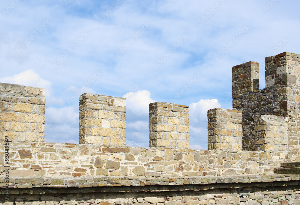  Merlons of ancient stone wall closeup, against blue cloudy sky, Sudak Genoese fortress, Crimea