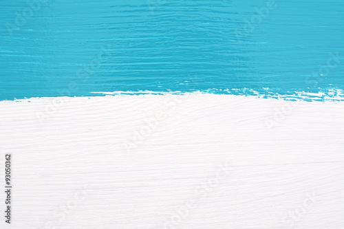 Stripe of teal paint over white wooden background