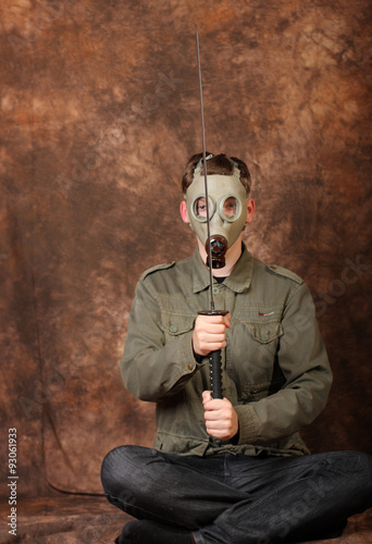 Man with gas mask and katana sword on brown batik background