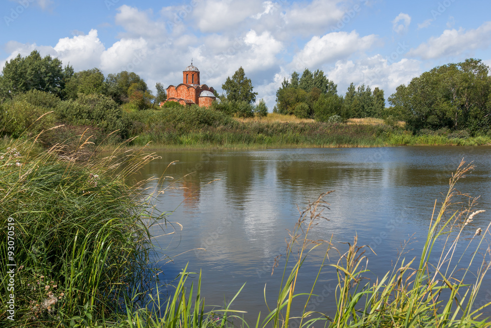 Old orthodox church on the bank of a pond on a summer day. Church of the Savior on Kovalev on the outskirts of Veliky Novgorod