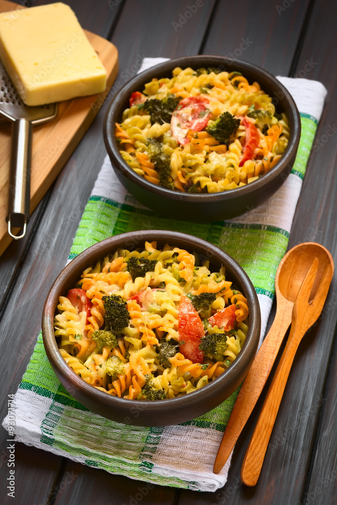 Baked tricolor fusilli pasta and vegetable (broccoli, tomato) casserole in rustic bowls, photographed with natural light (Selective Focus, Focus in middle of first dish) Baked tricolor fusilli pasta and vegetable (broccoli, tomato) casserole in rustic bowls, photographed with natural light (Selective Focus, Focus in middle of first dish)