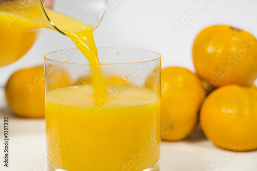 Filling a glass of natural tangerine orange juice