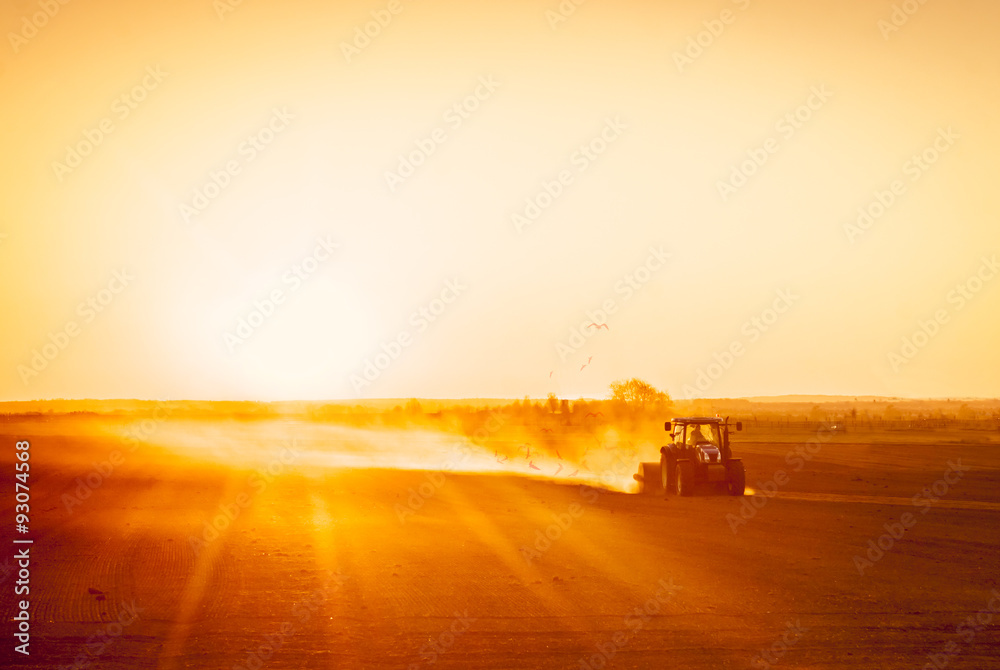 Obraz premium Farmer preparing his field in a tractor ready for spring