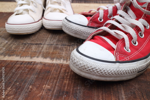 Original Valentine's Day love concept with red and white sneakers. Studio shot on a wooden floor background.