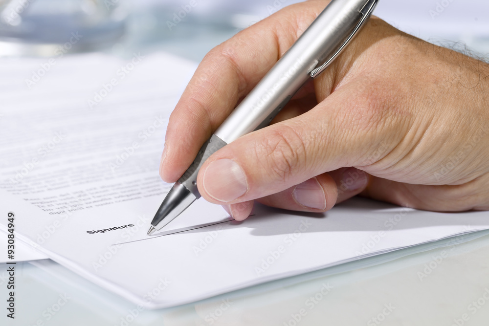 Close-up shot of hand signing a document Close-up shot of hand signing a document