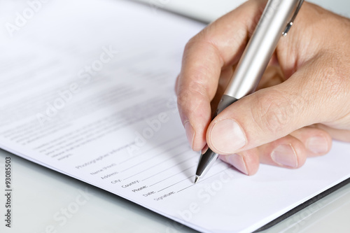 Close-up shot of hand signing a document photo
