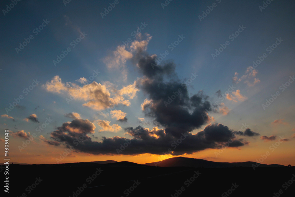 Fototapeta premium Promienie zachodzącego słońca zza chmur