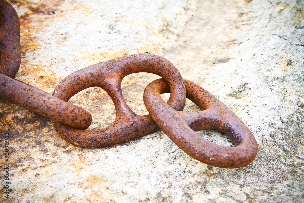 Detail of an old rusty metal chain anchored to a concrete block Detail of an old rusty metal chain anchored to a concrete block