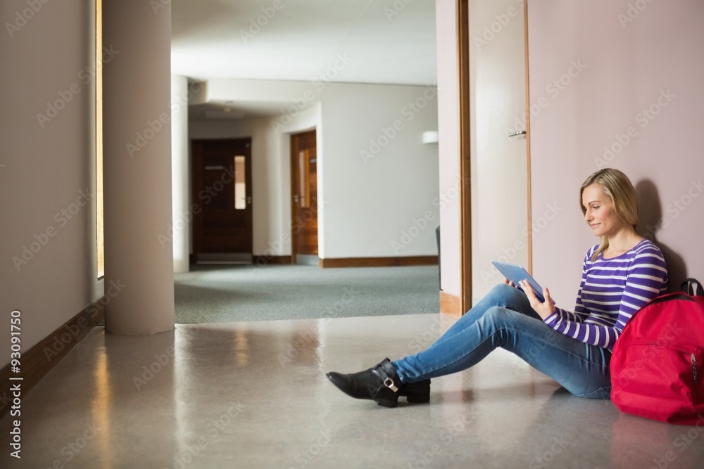Female student using digital tablet sitting by wall Female student using digital tablet sitting by wall