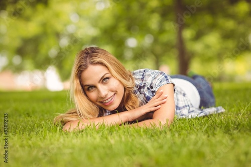 Portrait of smiling woman with arms crossed while lying on grass