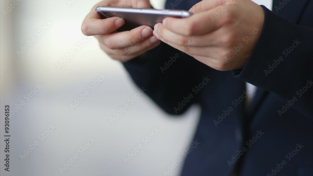 Tilt up shot of businesswoman using smart phone. Midsection of female professional is text messaging. She is in brightly lit office. Tilt up shot of businesswoman using smart phone. Midsection of female professional is text messaging. She is in brightly lit office.