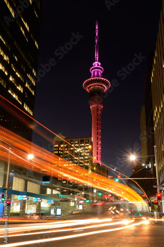Motion traffic light trail of vehicles in Auckland CBD in the foreground with the Sky Tower in the background at dusk. Vertical