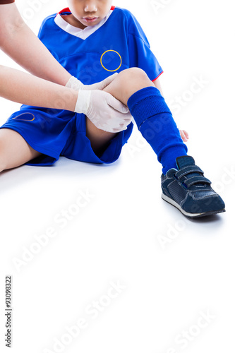 Sports injury. Doctor first aid at thigh of child. Isolated