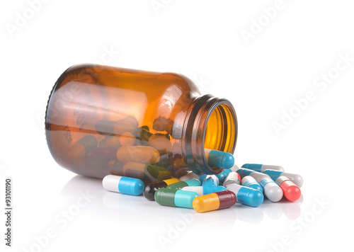 Pill bottle spilling pills on to surface isolated on a white bac