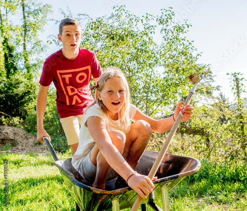 Photography A teenage boy carrying a young girl child in a wheelbarrow