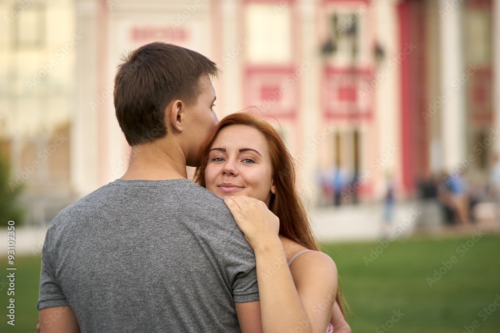woman looks out from behind a man woman looks out from behind a man