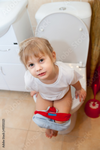 Toddler girl sitting on toilet