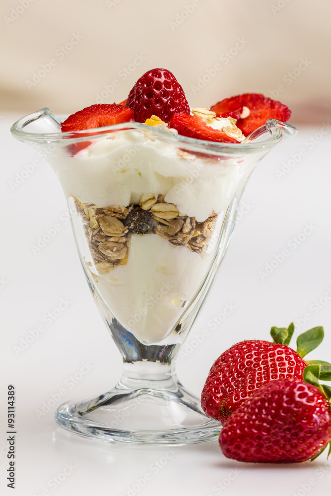 Glass of Muesli with strawberries and yogurt isolated on white