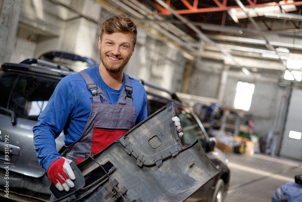 Fototapeta premium Mechanic with car bumper in a workshop