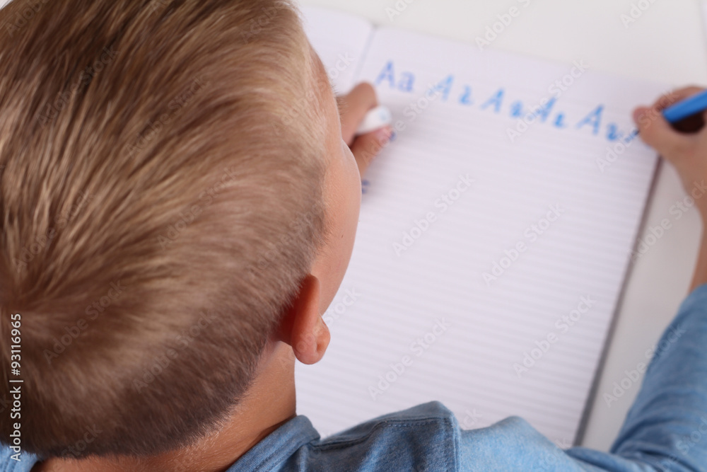 8 year old elementary school age boy writing the alphabet with Pencil . Kid, homework, education concept. Selective focus image 8 year old elementary school age boy writing the alphabet with Pencil . Kid, homework, education concept. Selective focus image