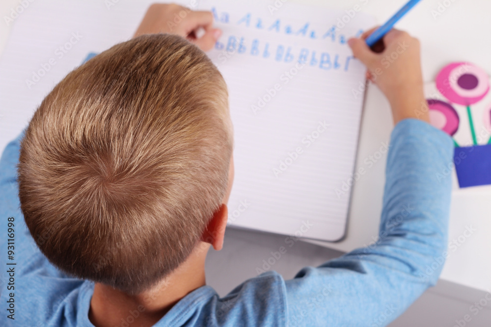 8 year old elementary school age boy writing the alphabet with Pencil . Kid, homework, education concept. Selective focus image 8 year old elementary school age boy writing the alphabet with Pencil . Kid, homework, education concept. Selective focus image