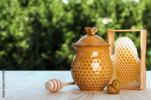 honeycomb and honeypot on a background of trees photo