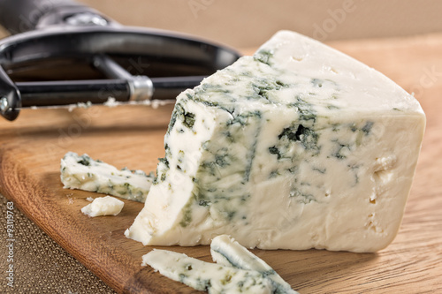 Slices of blue gorgonzola cheese on a board with wedge and slicer
