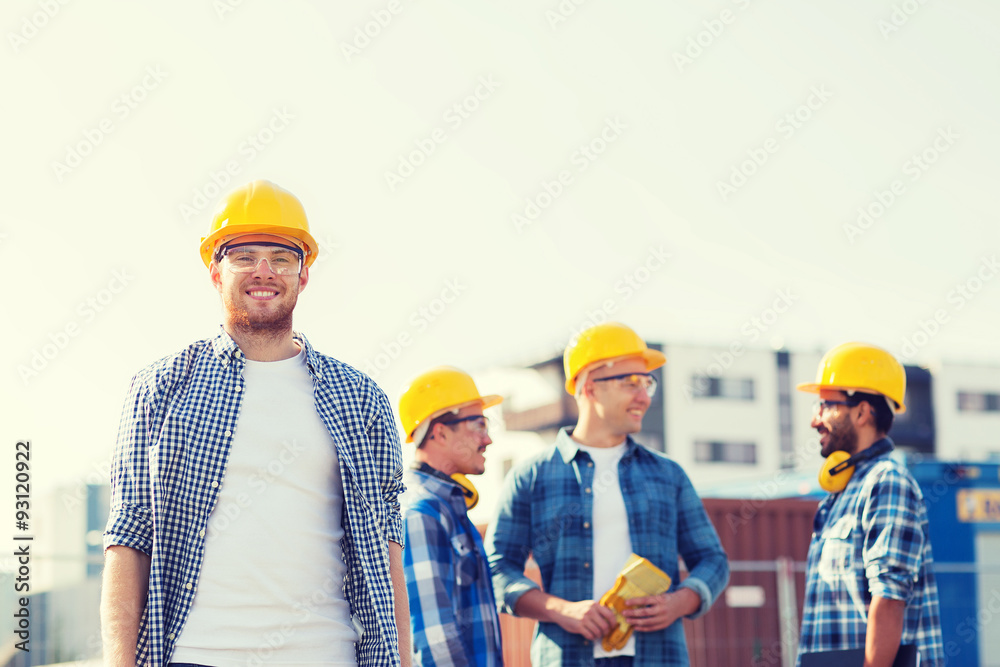 group of smiling builders in hardhats outdoors group of smiling builders in hardhats outdoors