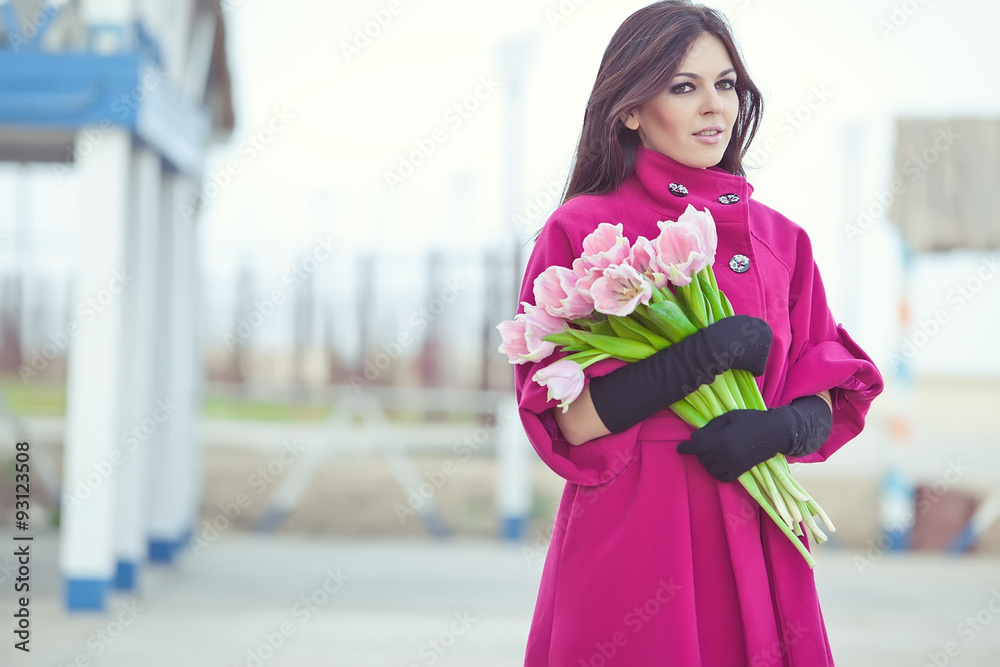 Fototapeta premium Beautiful woman are walking with a bouquet of tulips in a cities streets