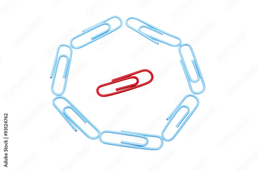 Circle of blue paper clips surrounding one red paper clip. Focus is on red paper clip.