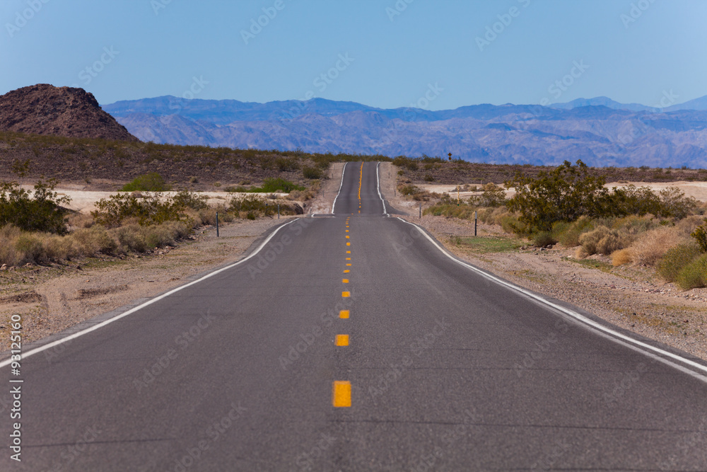 Straight road with lines in desert, California