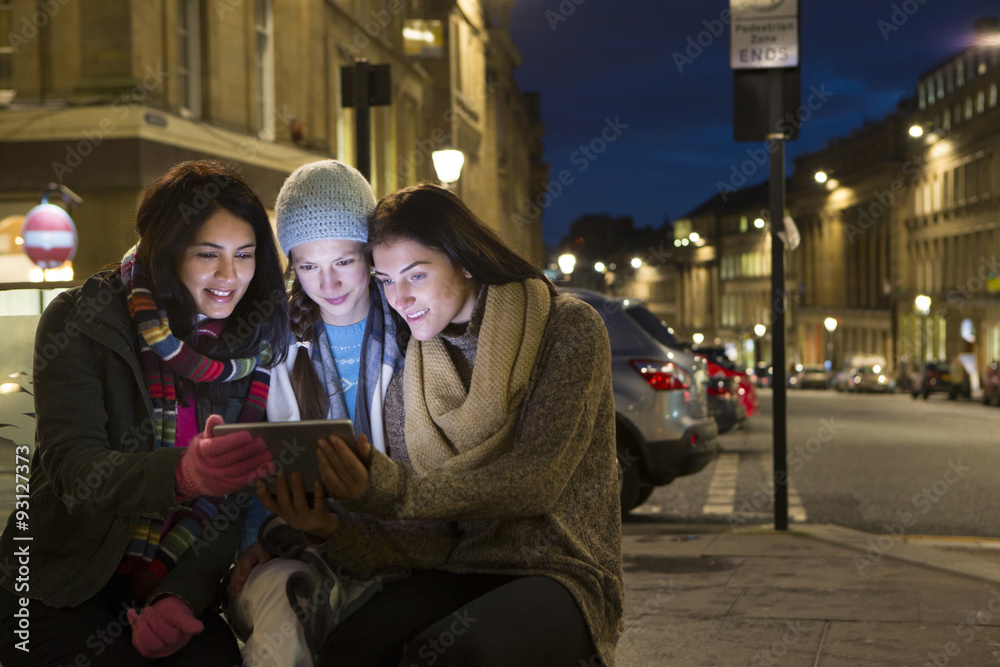 Three women looking at a digital tablet in the city