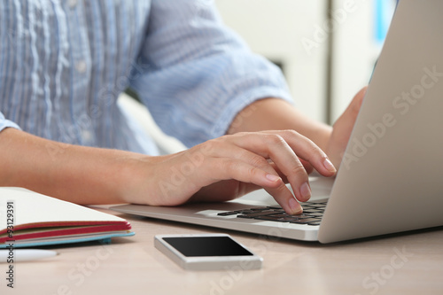 Woman using laptop on workplace close up