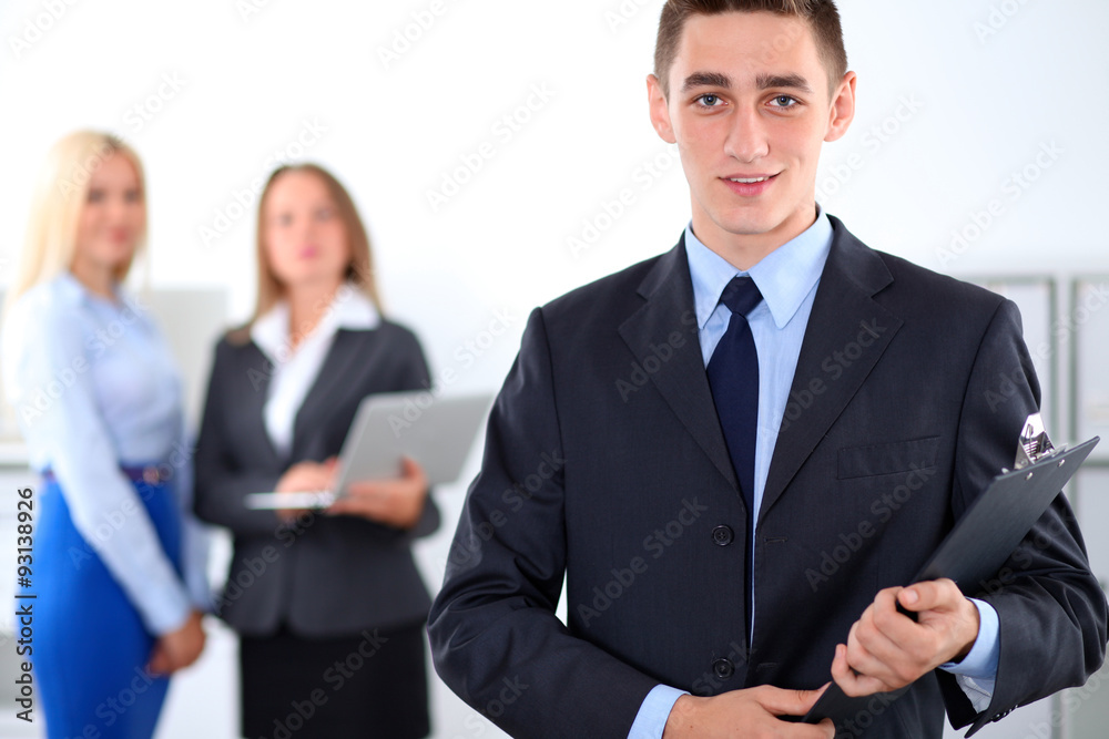 Cheerful business man in office with colleagues in the background, sturt-up team Cheerful business man in office with colleagues in the background, sturt-up team